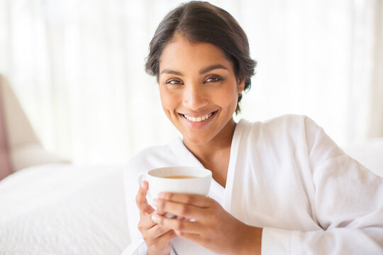 Portrait smiling woman in bathrobe drinking tea