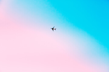 Airplane flying in the sky at pink sunrise. Traveling concept.