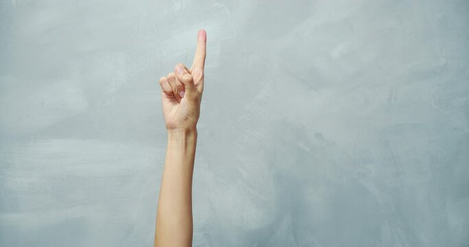 Close up of female hand counting from 1 to 5 showing fingers on gray background. Hand gesture. Numbers calculation.