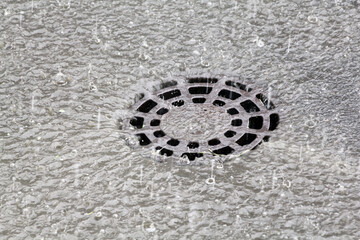 Sewer riser with perforation in the form of symmetrical circles, mounted in the asphalt.