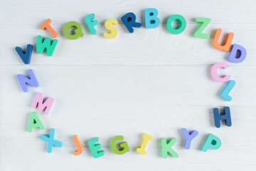 Close up Multicolored wooden letters with ABC on white wooden background. Set of toys for studying alphabet. Education, back to school concept. Top view, copy space