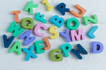 Close up Multicolored wooden letters with ABC on white wooden background. Set of toys for studying alphabet. Education, back to school concept. Top view, copy space
