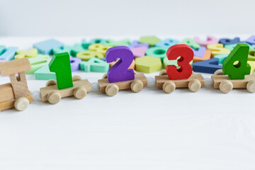 Close up Multicolored wooden letters on white wooden background. Set of toys for studying alphabet. Education, back to school concept. Top view, copy space