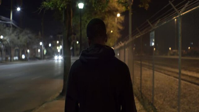 African American Teen Walks Down Street at Night, Behind Medium