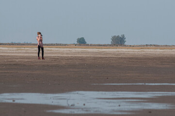 Fototapeta na wymiar Young, slim woman taking pictures on a lagoon's beach
