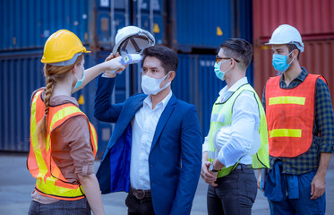 The worker used a medical Digital  temperature Thermometer to check staff body temperature before start work in factory ,they wearing face mask the concept of a corona virus [Covid-19] screening.