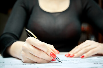 Woman with a magnificent bust fills documents close up with blur