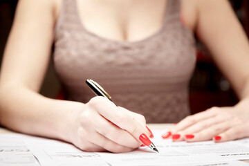 Woman with a magnificent bust fills documents close up with blur