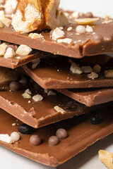 Close-up of a pyramid of delicious milk chocolate with nuts and waffle balls.
