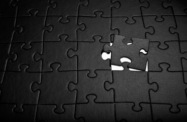 Puzzles in black. Monochrome cardboard shapes. Dark background.
