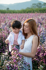 Asian mom with her son in a flowering field of margaret.