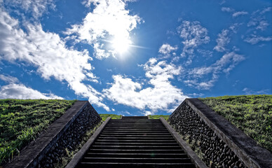 Looking up at a deep blue sky  and concrete steps leading up a grassy hill on a sunny day in late...