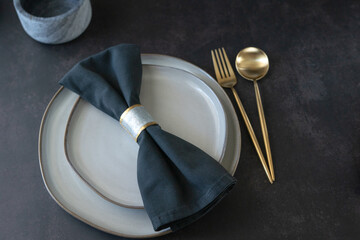 Empty plates and golden cutlery set on a black table