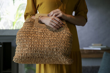 Close up shot of woman holding handmade rattan woven bag