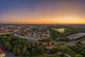 Obraz premium Wide view over Munich at the morning, where the popular green park called Englischer Garten is covered by fog. Panoramic sunrise view from a drone.