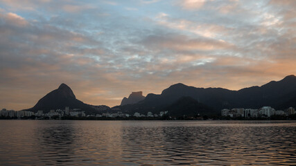 Rio de Janeiro city lake Lagoa Rodrigo de Freitas with Two Brothers and Gavea mountain reflecting in the water against a golden hour cloudy sunset