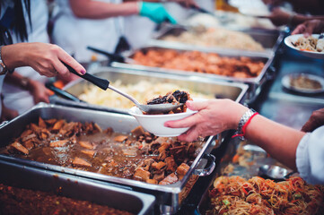 Providing free food to the poor : Volunteers scooping out food to give charity to those who are...