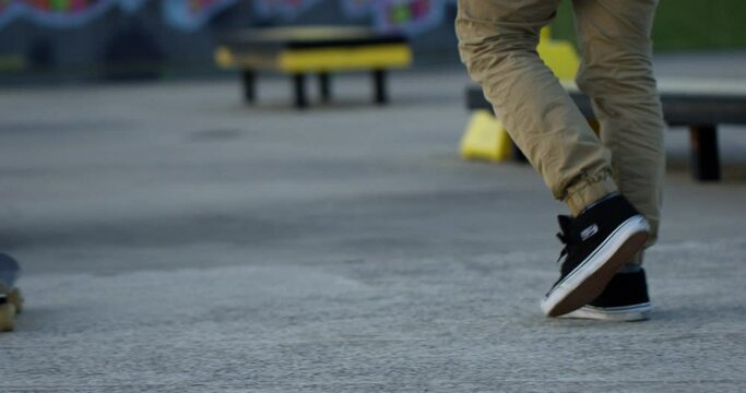 Skateboard walks back to skatepark - close up on feet
