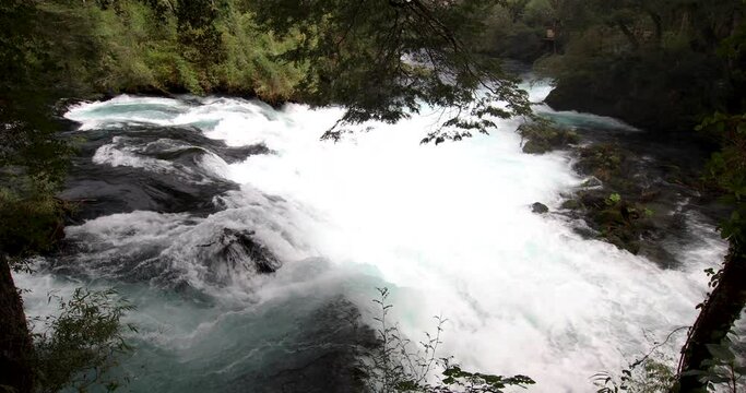 The wild white waters of Caburgua River flowing down and jumping at Carileufu waterfall. An amazing scenery inside the south of Chile rainforest at Pucon, an idyllic landscape for some relax time
