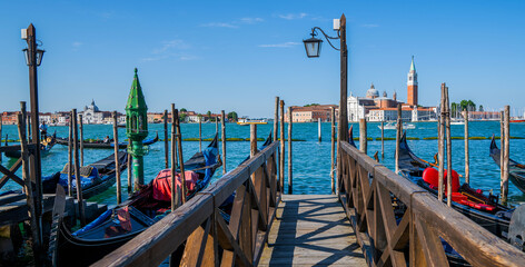 Fototapeta na wymiar Gondolas moored by Saint Mark square with San Giorgio di Maggiore church in the background in Venice, Italy. Architecture and landmarks of Venice.