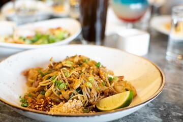 Close up image of Thailand traditional street food, Pad Thai noodles on a white plate and marble stone table.