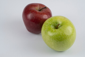 Green and red apples on a white background near each other
