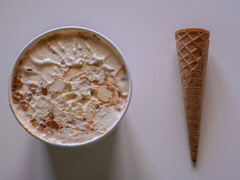 Sweets to eat during the summer. A biscuit and caramel ice cream inside a large white box and a waffle cone at its side.