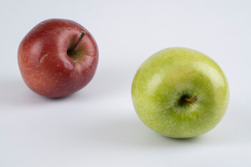 Green and red apples on a white background near each other