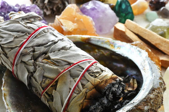 A close up image of a white sage bundle and several energy healing crystals. 