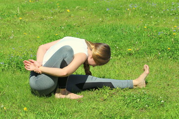 Young woman of European appearance does yoga in summer nature
