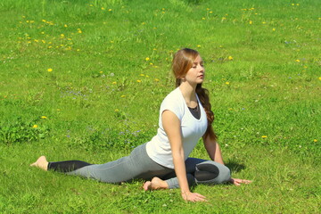 Young woman of European appearance does yoga in summer nature
