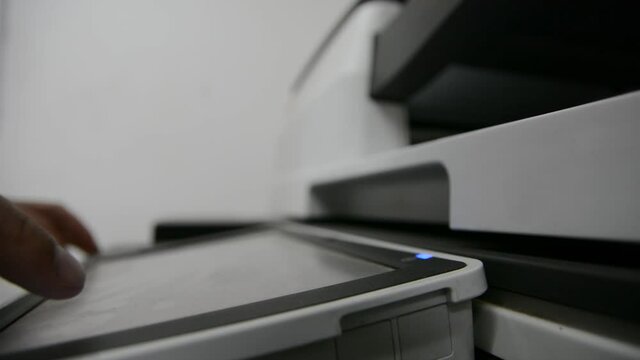 : Close up low light. Someone work on modern copy machine at office.