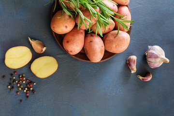Raw red potatoes with fresh rosemary and garlic on blue background. Organic food
