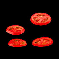 Flying tomato. Sliced red tomato isolated on black background. Levity vegetable floating in the air.