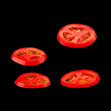 Flying tomato. Sliced red tomato isolated on black background. Levity vegetable floating in the air.