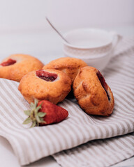 Strawberry muffin with fresh strawberries in a cut on a white wooden table.