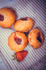 Strawberry muffin with fresh strawberries in a cut on a white wooden table.