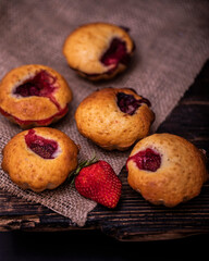 Tasty cupcake, decorated with fresh strawberry on a dark wooden background. Muffin with place for text.