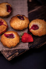 Tasty cupcake, decorated with fresh strawberry on a dark wooden background. Muffin with place for text.