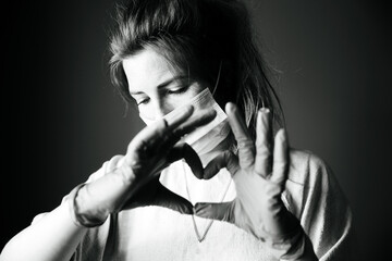 Young woman wearing protection mask against Covid-19, Coronavirus looking depressed and isolated, black and white portrait virus concept