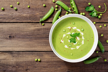Bowl of  green peas cream soup on wooden table