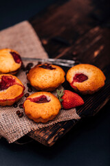 Strawberry chocolate cupcakes muffins on old wooden stand on concrete gray background.