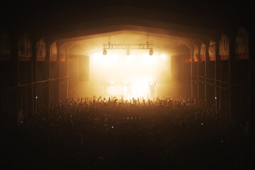 Silhouettes of a musical group with spotlights on stage and a full hall of a dancing crowd. atmosphere of a music festival. concert poster