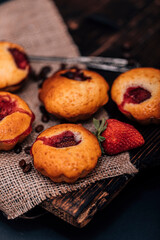 Strawberry chocolate cupcakes muffins on old wooden stand on concrete gray background.