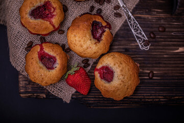 Strawberry muffin and coffee beans on a wooden board on a dark wood background. Chocolate muffins on dark background, selective focus.