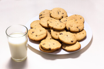 Delicious chocolate chip cookies plate with a glass of milk on a white background