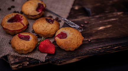 Strawberry muffin and coffee beans on a wooden board on a dark wood background. Chocolate muffins on dark background, selective focus.