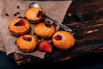 Obraz na płótnie Canvas Strawberry muffin and coffee beans on a wooden board on a dark wood background. Chocolate muffins on dark background, selective focus.