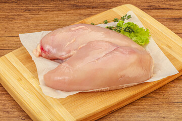 Raw chicken breast over board