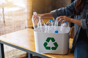 A woman collecting and separating recyclable garbage plastic bottles into a trash bin at home